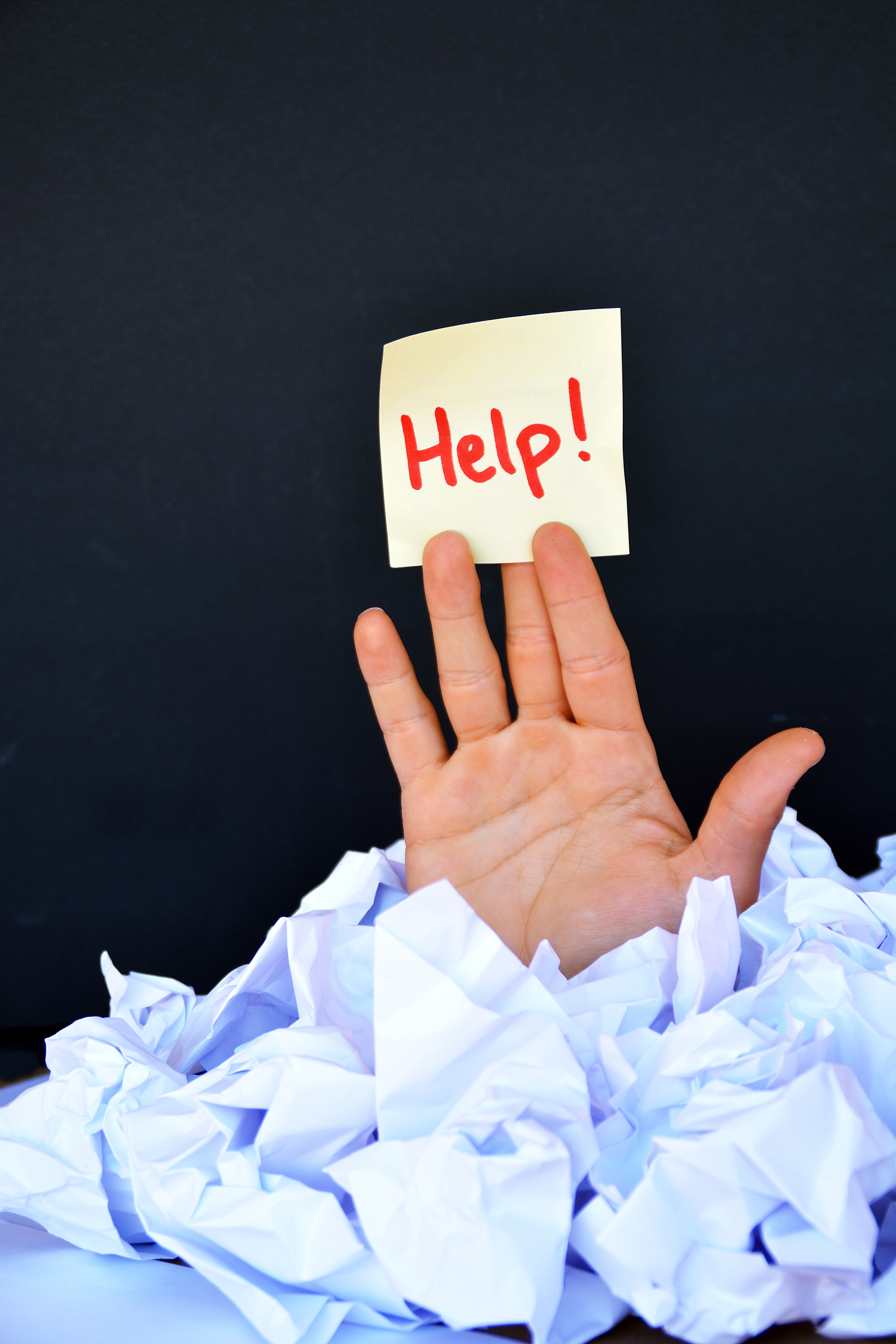 A hand reaching out from a pile of paperwork